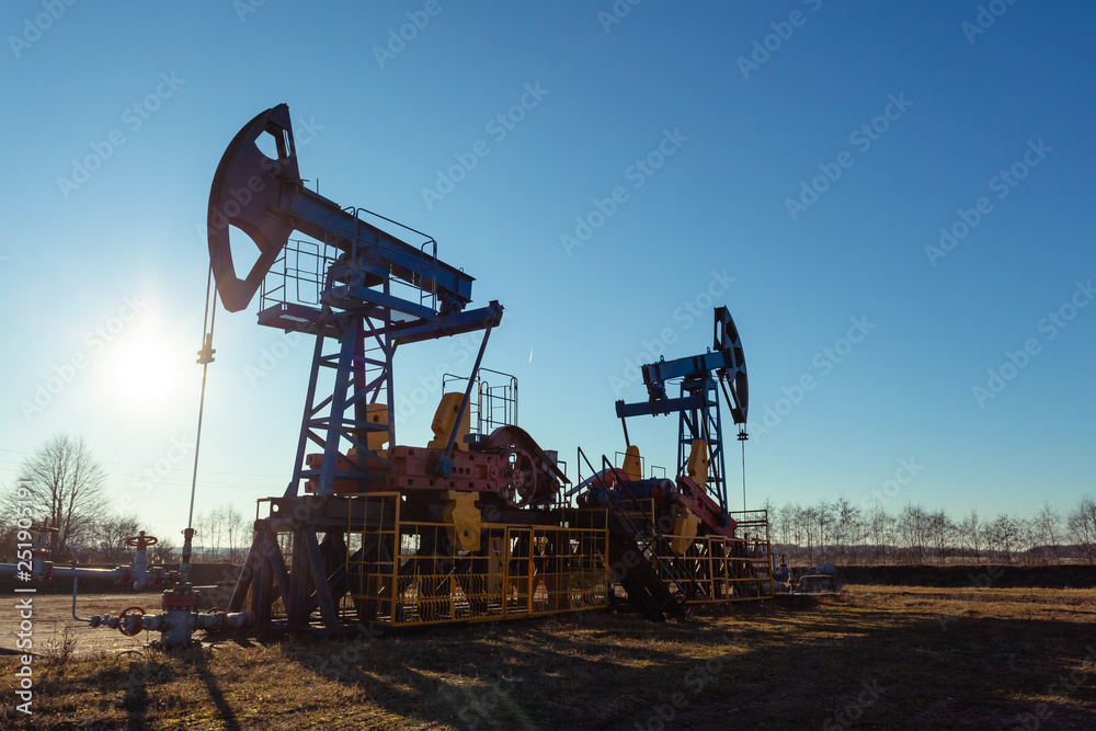 oil production tower while working against the bright sun and blue sky oil production tower while working against the bright sun and blue sky