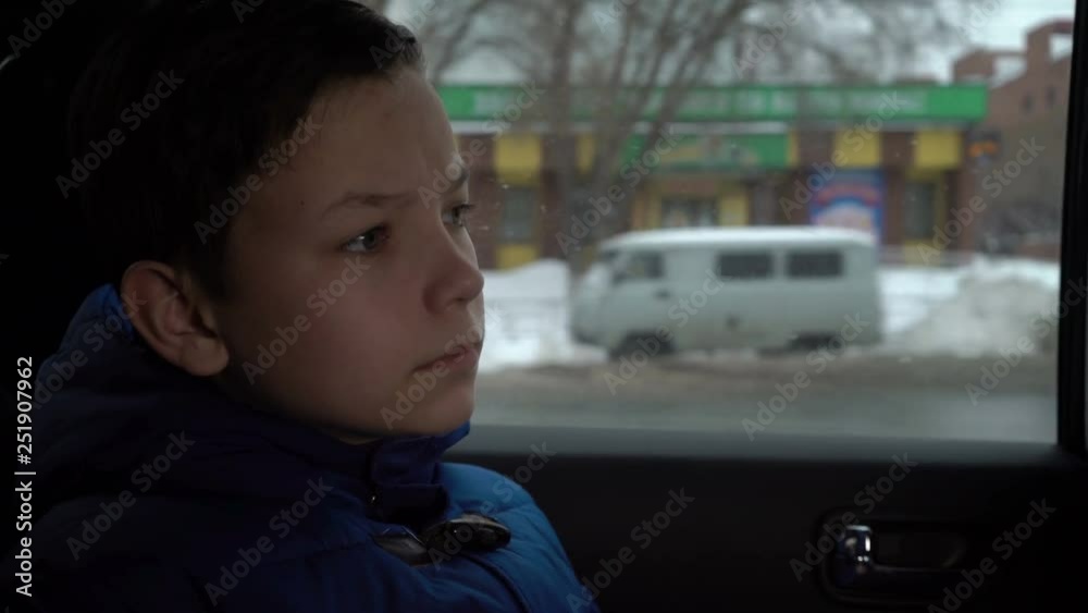 teenager looks out the car window in winter teenager looks out the car window in winter