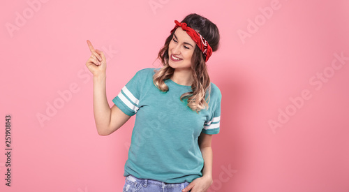 Portrait girl pointing her finger to the side on an isolated pink background