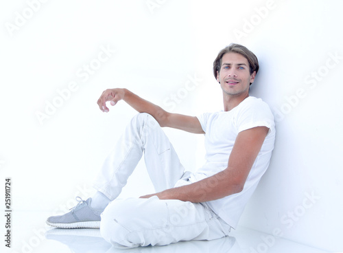 anxious man sitting beside a white wall