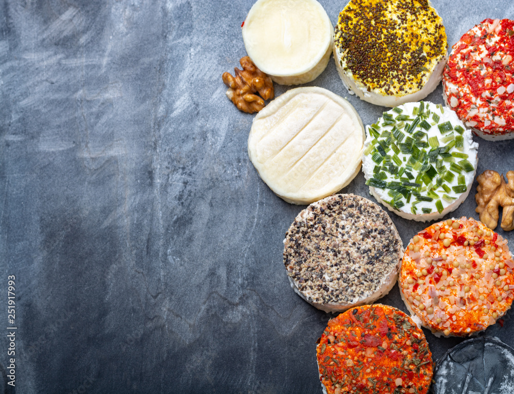 Assortment of French fresh white soft goat cheeses with different tastes topping made with herbs, paprika, indian curry, bruscetta, chives and dried tomatoes Assortment of French fresh white soft goat cheeses with different tastes topping made with herbs, paprika, indian curry, bruscetta, chives and dried tomatoes