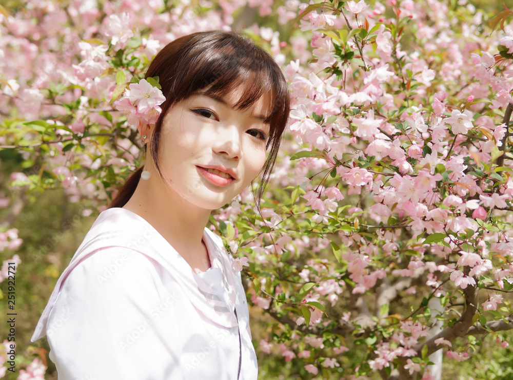 Outdoor portrait of beautiful young Chinese girl smiling among blossom cherry tree brunch in spring garden, beauty, summer, emotion, expression and people lifestyle concept. Outdoor portrait of beautiful young Chinese girl smiling among blossom cherry tree brunch in spring garden, beauty, summer, emotion, expression and people lifestyle concept.