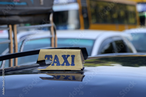 Broken taxi light sign or cab sign in drab yellow color with blue text on the car roof.