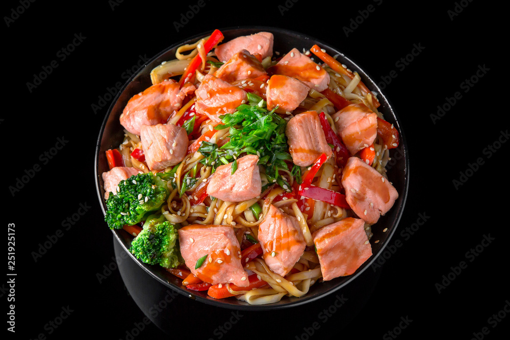 Soba, udon, asian wheat noodles ramen with salmon and vegetables: broccoli, carrots, sweet peppers, zucchini on a black background. Asian style. Japanese food Soba, udon, asian wheat noodles ramen with salmon and vegetables: broccoli, carrots, sweet peppers, zucchini on a black background. Asian style. Japanese food