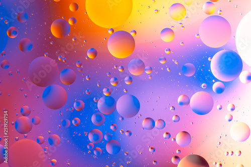 purple and orange oily drops  in water with colorful background, close-up 