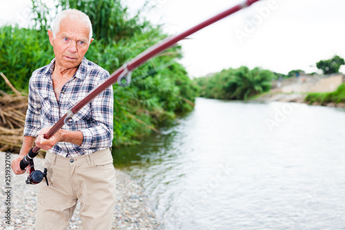 Aged fisherman pulling out catch