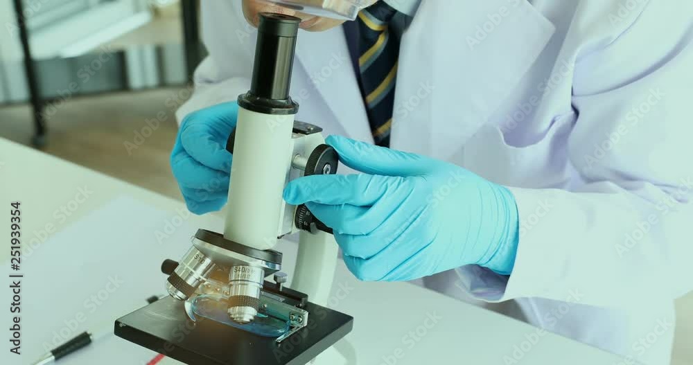 Scientist adjusting the microscope for his experiments, in laboratory room. Scientist adjusting the microscope for his experiments, in laboratory room.