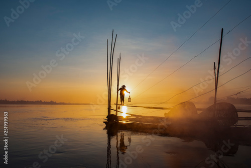 Fototapeta Naklejka Na Ścianę i Meble -  Asian fishermen hold fishing equipment on their boats to wait for fish in the Mekong River. In the morning of the new day