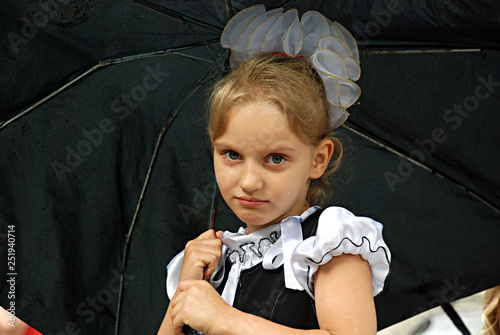upset first-grader schoolgirl with black umbrella