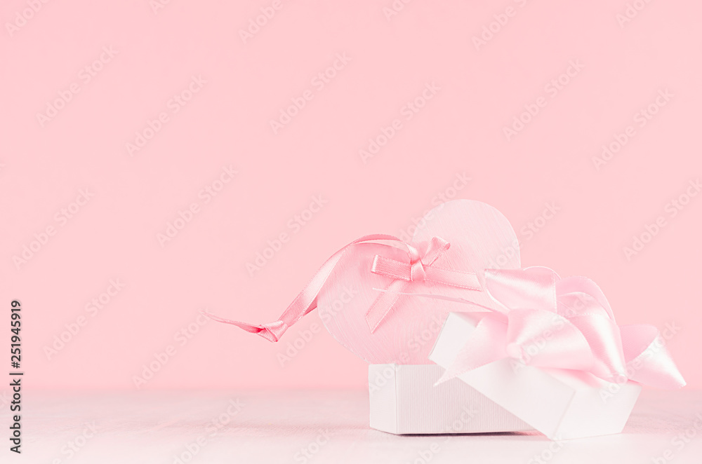 Gentle decor for Valentine days - soft light pink heart with ribbon and present box on white wood board, copy space.