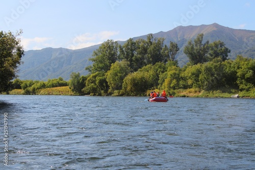 View of Bystraya Malkinskaya river on the Kamchatka Peninsula, Russia. Tourists on orange raft are visible on water.