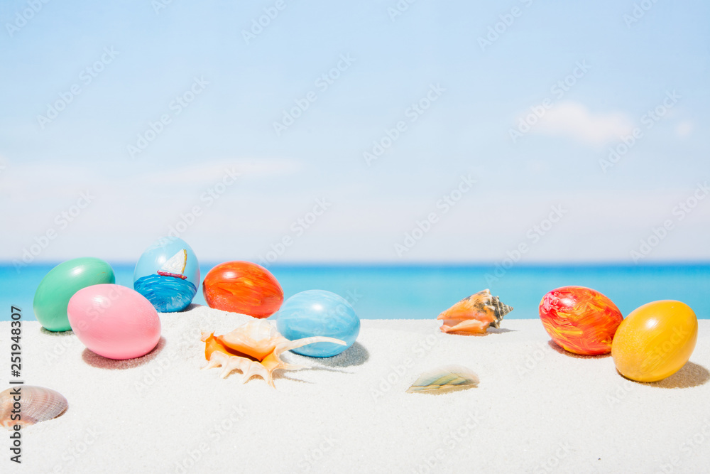 Obraz premium Easter on tropical beach background. Eggs on the white sand. Vacation and travel concept in spring