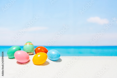 Easter on tropical beach background. Eggs on the white sand. Vacation and travel concept in spring