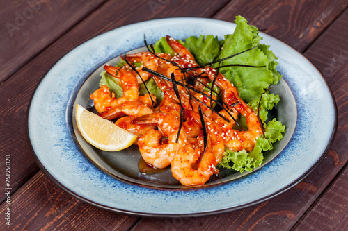  large and appetizing ready-made shrimps beautifully laid out with greens and vegetables for design solutions in cooking