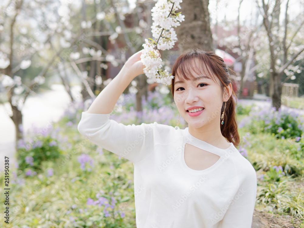 Outdoor portrait of beautiful young Chinese girl smiling among blossom cherry tree brunch in spring garden, beauty, summer, emotion, expression and people lifestyle concept. Outdoor portrait of beautiful young Chinese girl smiling among blossom cherry tree brunch in spring garden, beauty, summer, emotion, expression and people lifestyle concept.