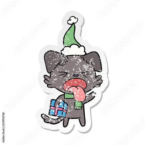 distressed sticker cartoon of a disgusted dog with christmas gift wearing santa hat