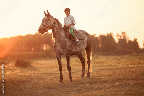 Young boy confident galloping horse on the field