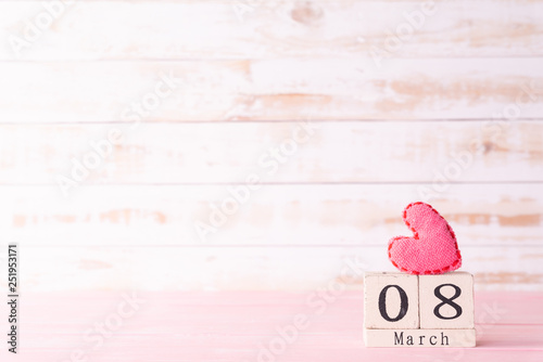 International Womens day concept. March 8 text on wooden block with handmade pink heart on white wooden background. photo