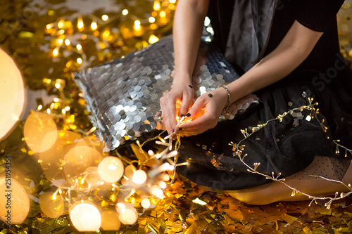 Amazing cute lady celebrating new year birthday party, posing in gold shine background and throwing colorful confetti with silver baloons.