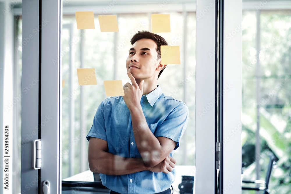 Young Asian Businessman Working in Office Meeting Room. Man Analyzing Data Plans and Project. Concentrate on Document Note on Board Young Asian Businessman Working in Office Meeting Room. Man Analyzing Data Plans and Project. Concentrate on Document Note on Board