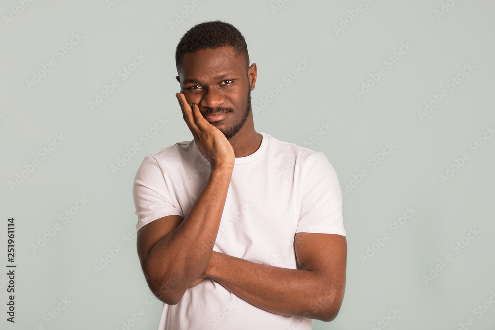 adult African man in a white T-shirt with a sad face on a blue background adult African man in a white T-shirt with a sad face on a blue background