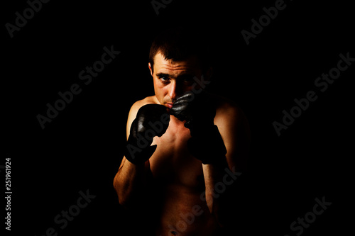 A man in gloves for fighting without rules MMA on a black background. Workout concept  combat training