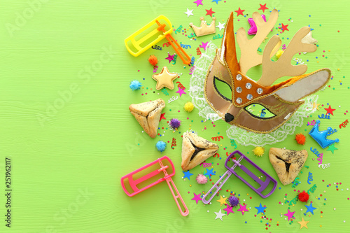 Purim celebration concept (jewish carnival holiday) over wooden green background photo