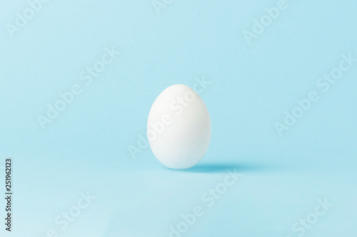 White Chicken Egg on a blue background. Minimalism. Side view