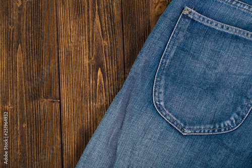 Frayed jeans or blue jeans denim collection on rough dark wooden table background, top view with copy space, old fashion concept.