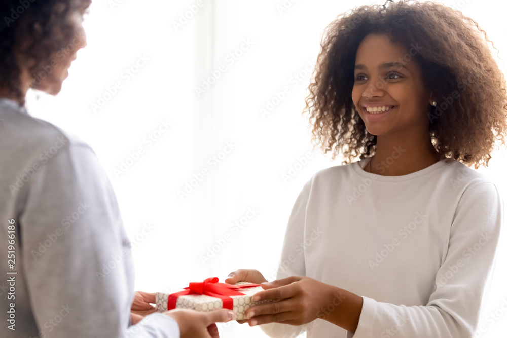 Happy mixed race daughter giving present to beloved mother Happy mixed race daughter giving present to beloved mother