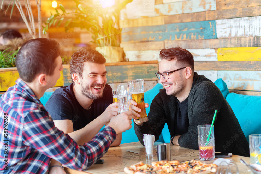 Happy young male friends drinking beer at trendy pub