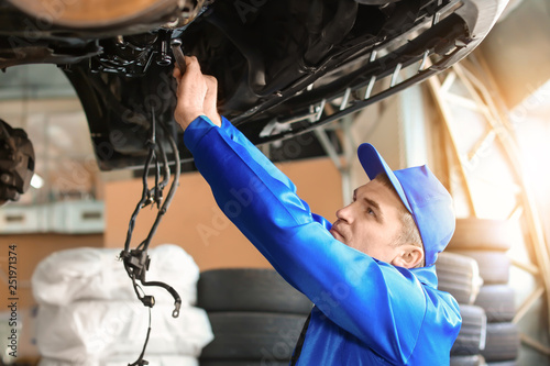 Male mechanic fixing car in...