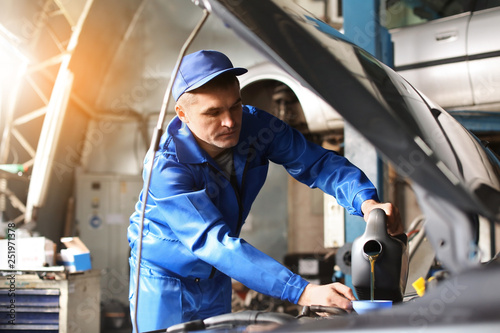 Male mechanic refilling car...