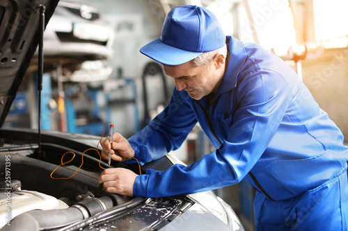 Male mechanic examining car...