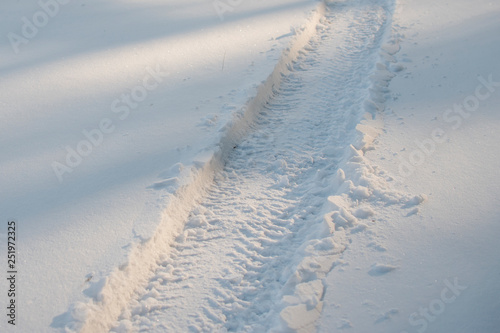 Snowy tire track from a car going through deep snow.