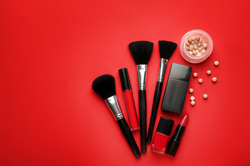 Set of makeup brushes and cosmetics on color background