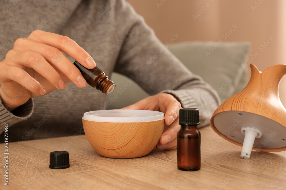 © Pixel-Shot - Woman filling essential oil diffuser, closeup