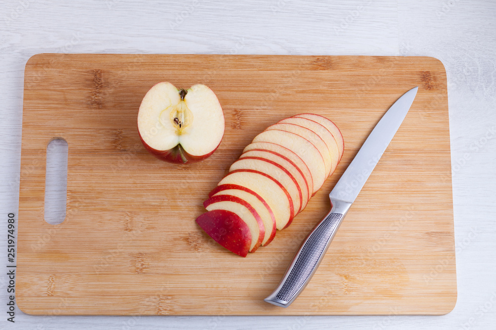 Knife and cut apples on a wooden cutting board. Apples cut into slices with a metal knife Knife and cut apples on a wooden cutting board. Apples cut into slices with a metal knife