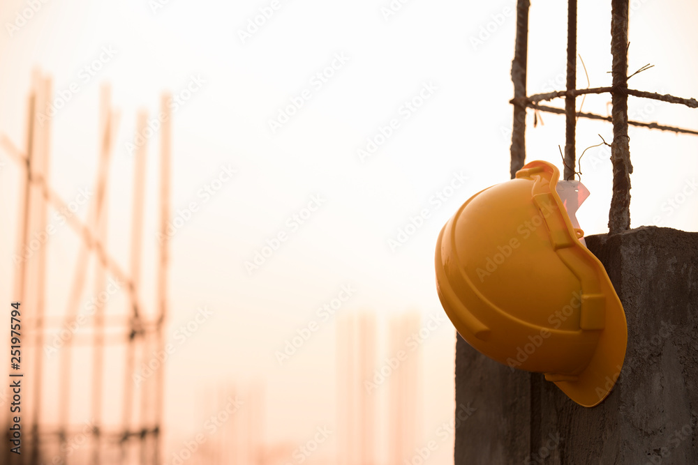 Helmet hanging on the Reinforced concrete pole ,helmet in construction site and sunset,Safety helmets for workplace construction,Sunrise or sunset background