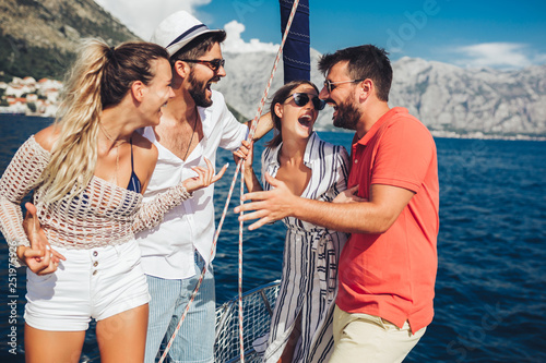 Smiling friends sailing on yacht - vacation, travel, sea, friendship and people concept