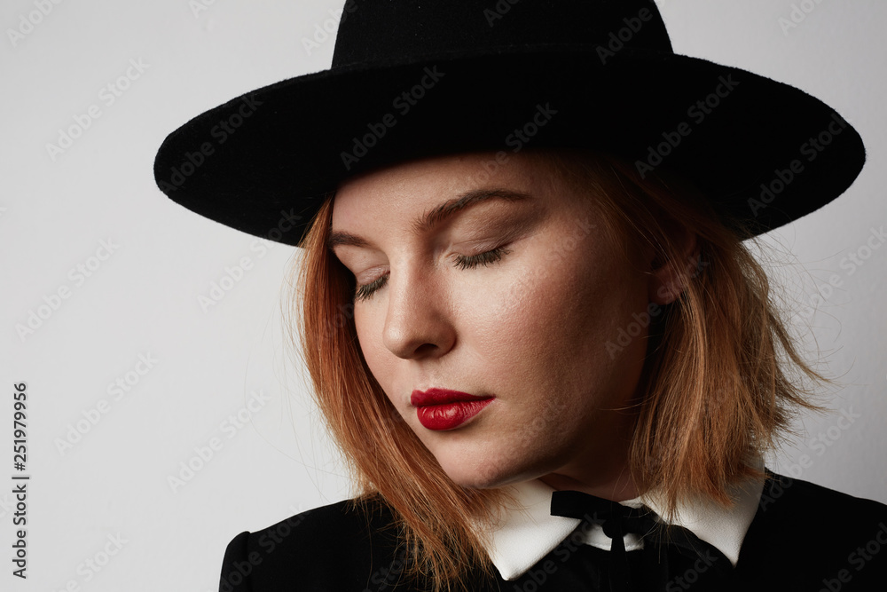 Close up fashion portrait of gorgeous woman in stylish clothes and black hat posing on white background Close up fashion portrait of gorgeous woman in stylish clothes and black hat posing on white background