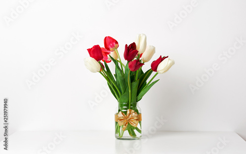 Fototapeta Naklejka Na Ścianę i Meble -  tulip flowers are in a vase on the table, white wall as background