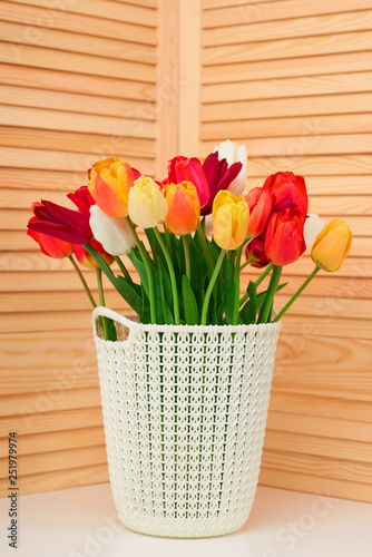 tulip flowers are in a basket on the table, wood background