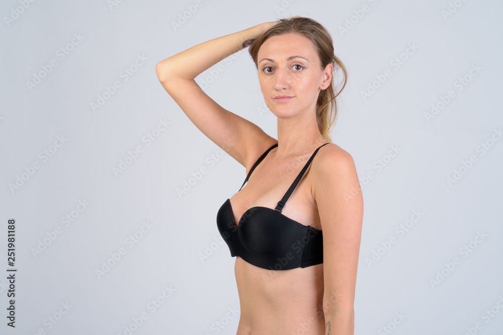 Fototapeta premium Portrait of blonde woman in bikini holding hair up
