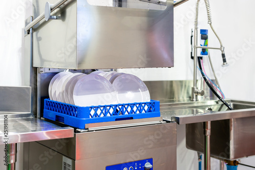 close up white plate on basket in automatic dishwasher machine for industrial