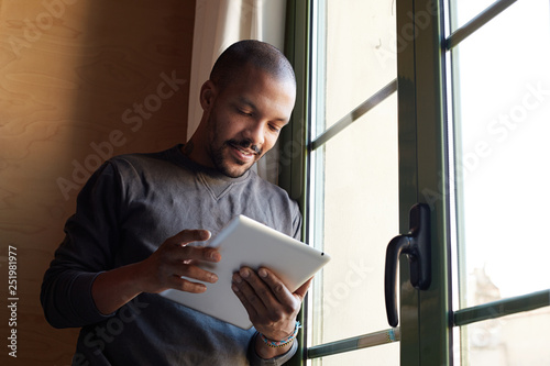 Happy African black man using tablet at home living room