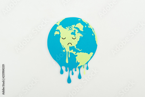 Fototapeta Naklejka Na Ścianę i Meble -  melting paper cut globe with sad face expression on grey background, global warming concept