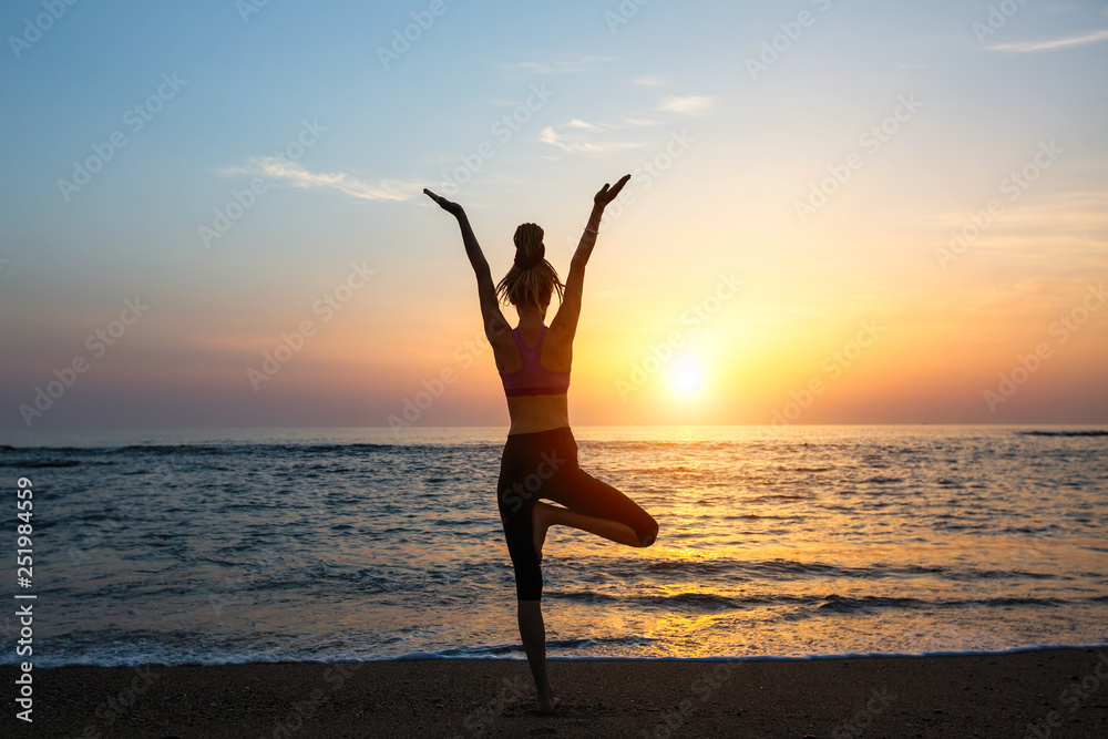 Yoga woman silhouette on the sea during amazing sunset.