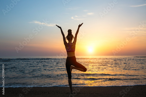 Yoga woman silhouette on the sea during amazing sunset.