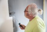 Funny senior man painting the wall